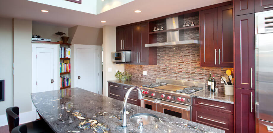 custom chocolate cherry wood kitchen cabinetry complimented by steel colored stone slab