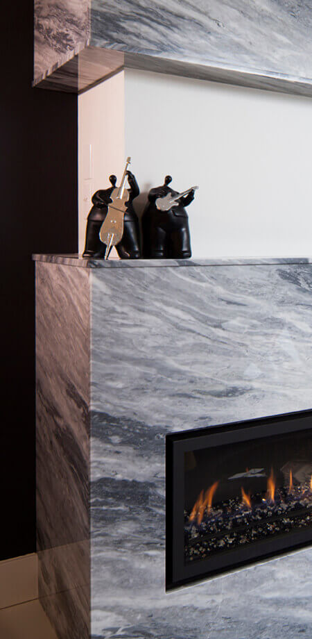 Close up detail of granite wrapped corner of fireplace that ties two spaces of this home together