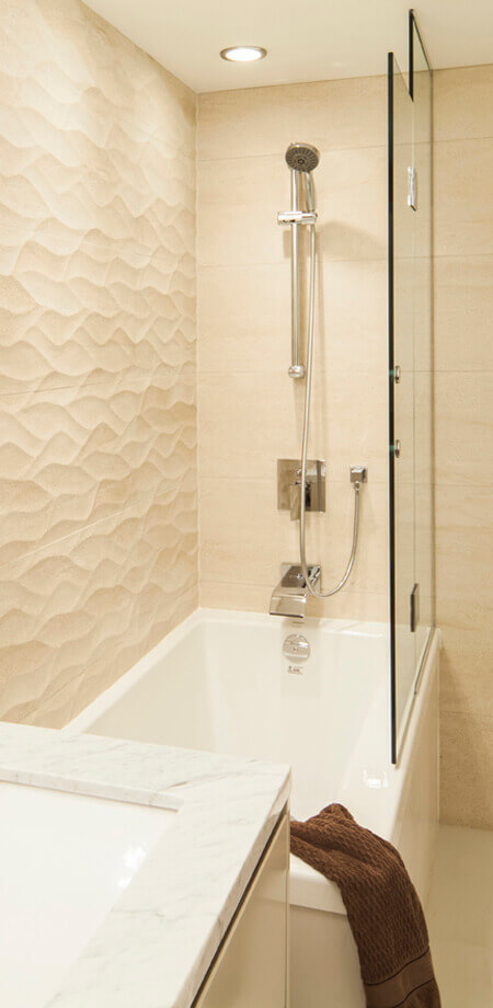 Bath with limestone feature wall and glass partition in Vorth Vancouver high end bathroom renovation
